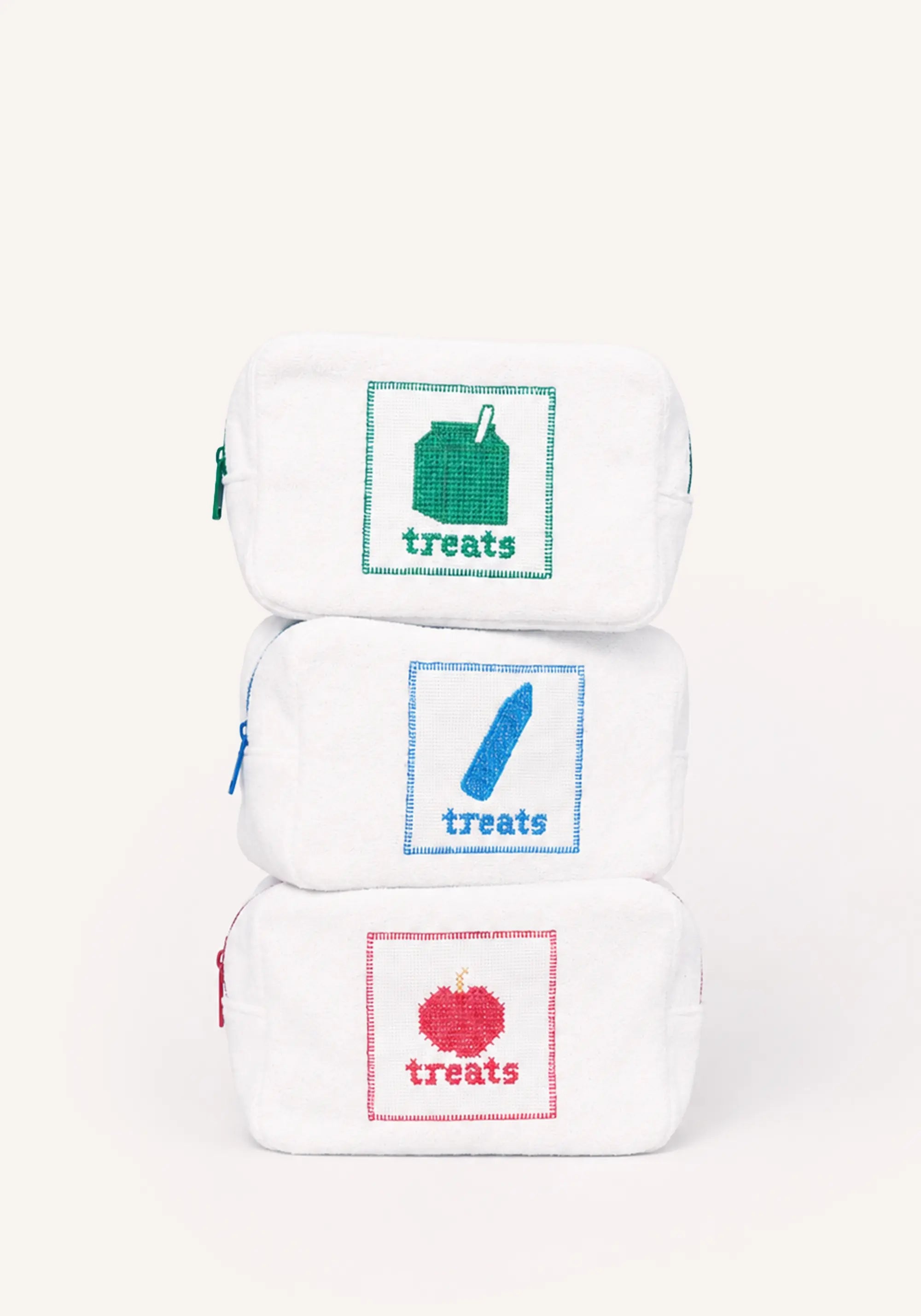 Three white zippered pouches stacked vertically on a white background, each with a colored square graphic and the word 'treats' underneath: green for the top pouch, blue for the middle, and red for the bottom.