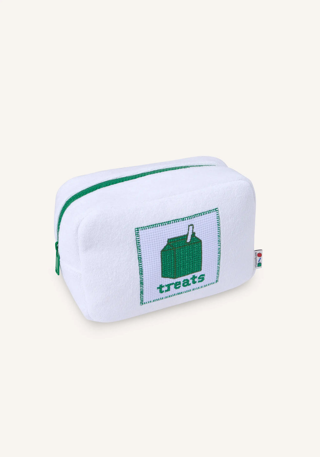 A white fabric zippered pouch with green zipper trim and a green cross-stitch style patch featuring a milk carton and the word 'treats' on the front, shown on a light cream background.