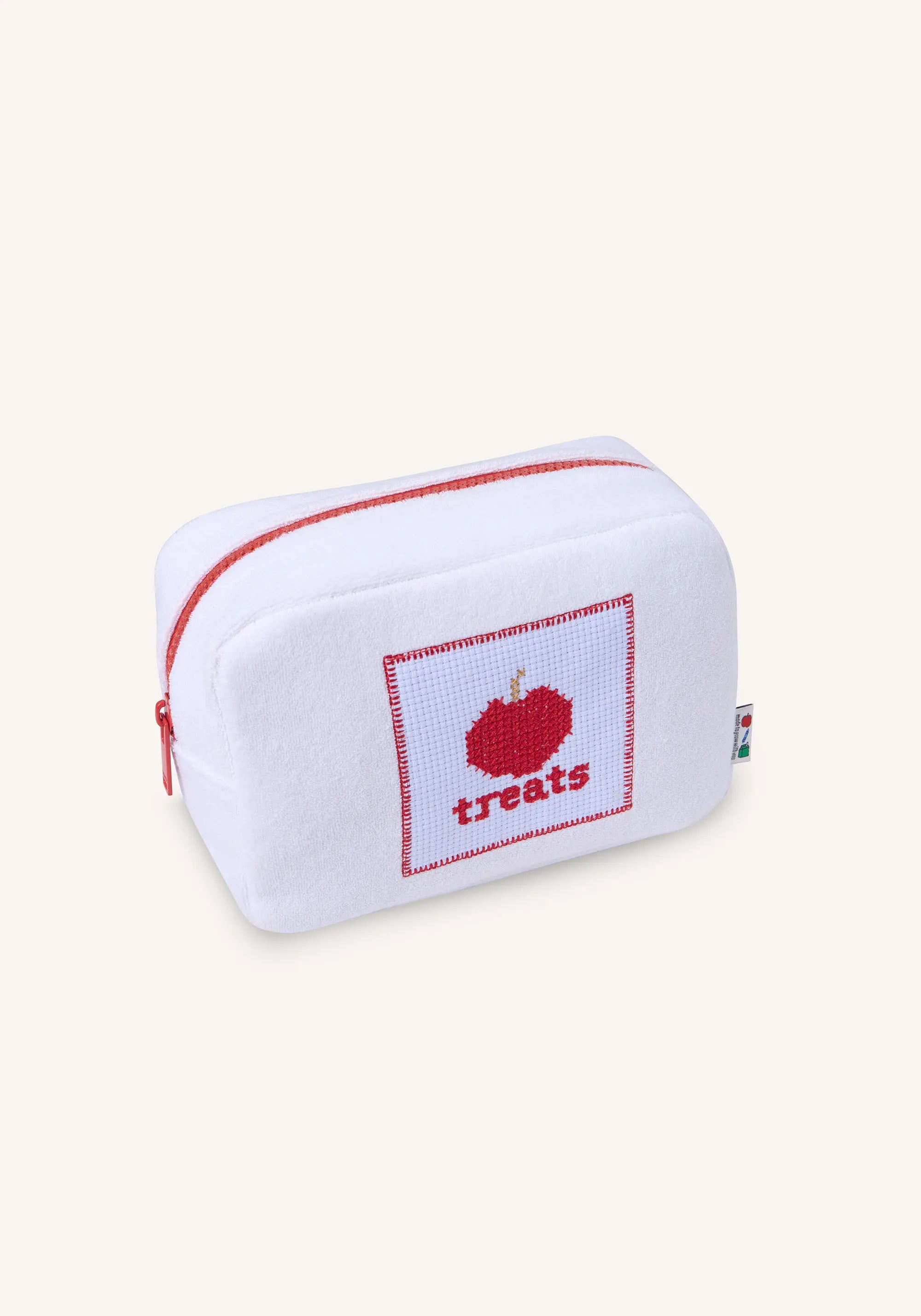 A white cross-stitch style pouch with red trim and a red stitched apple design containing the word 'treats', shown on a plain light beige background.